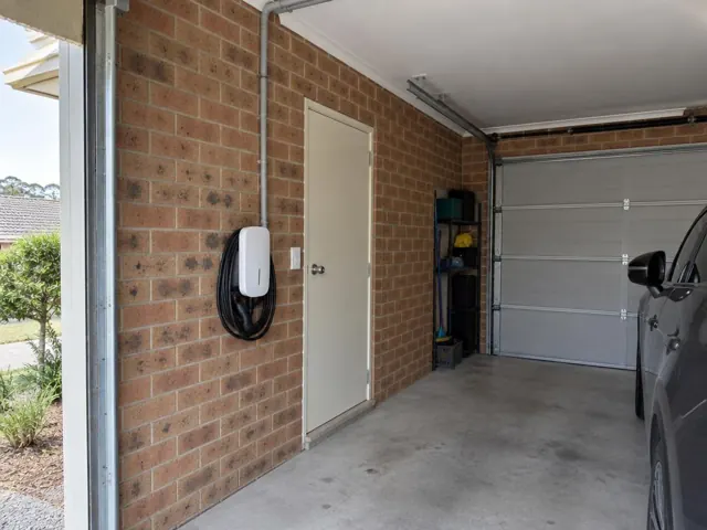 EV charger mounted on a brick garage wall beside a door in Mount Colah